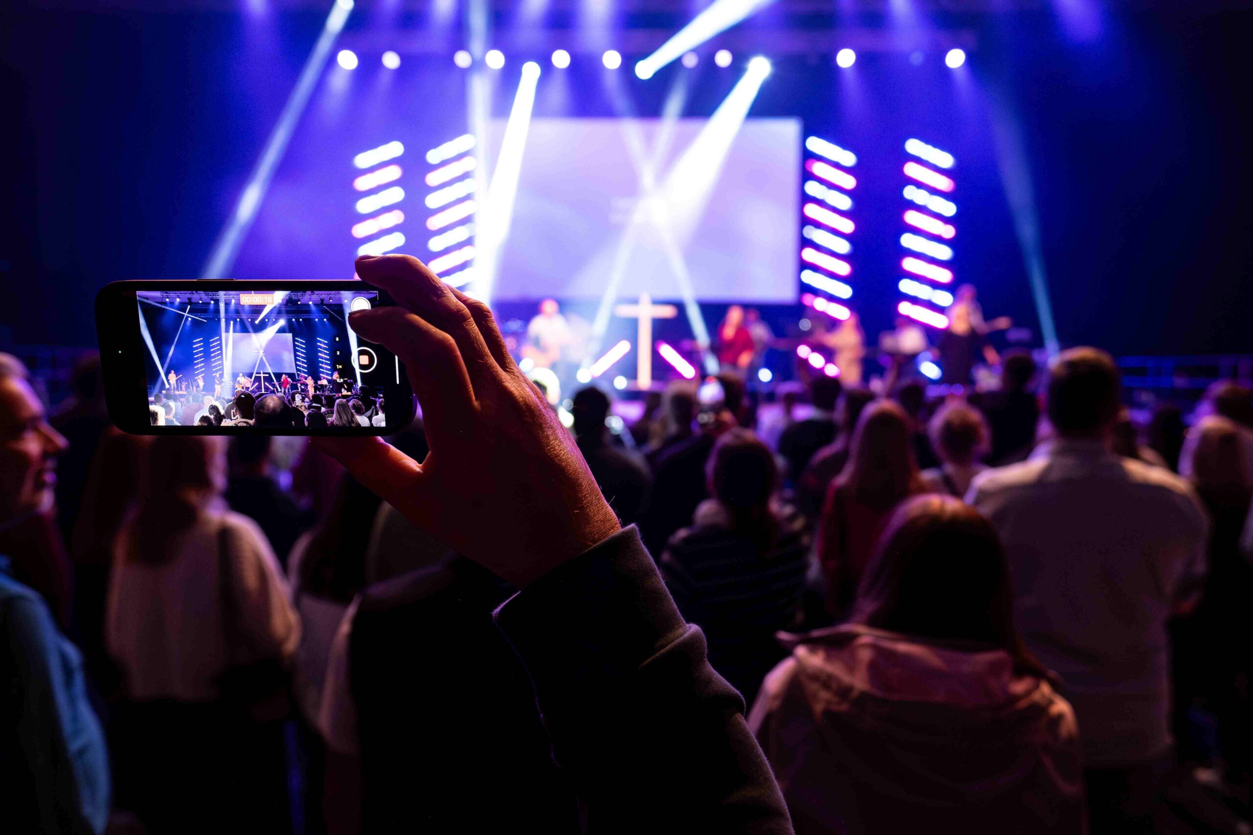 Eon Besucher fotografiert beim Lobpreiskonzert mit seinem Handy die Bühne.