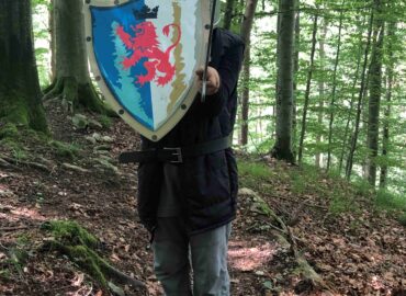 ein kind steht im wald mit ritterrüstung, Helm und schild