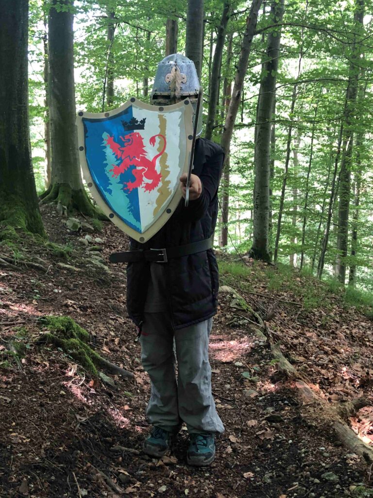 ein kind steht im wald mit ritterrüstung, Helm und schild